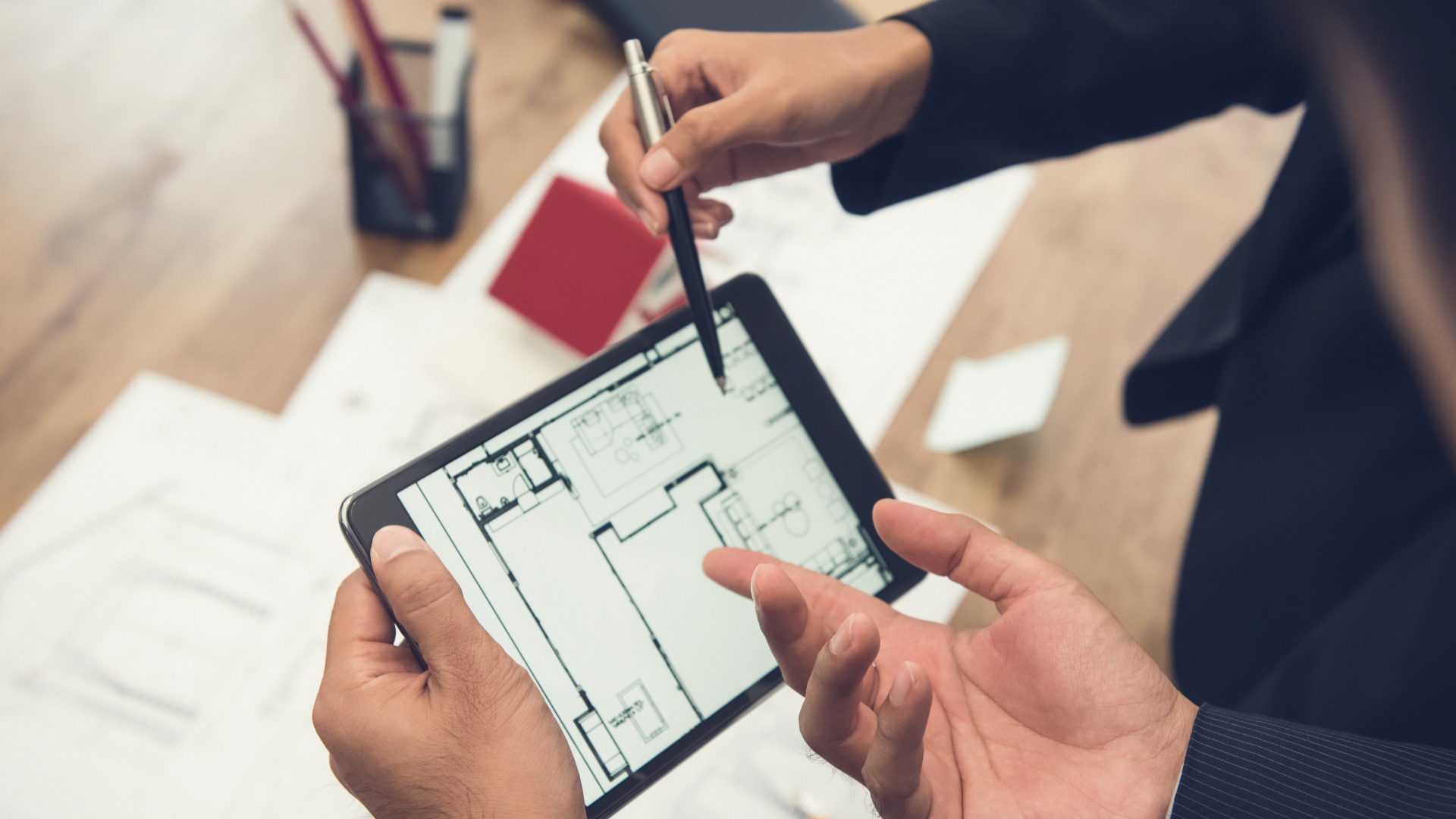 Real estate agent with client or architect team checking a housing model and its blueprints digitally using a tablet jpg